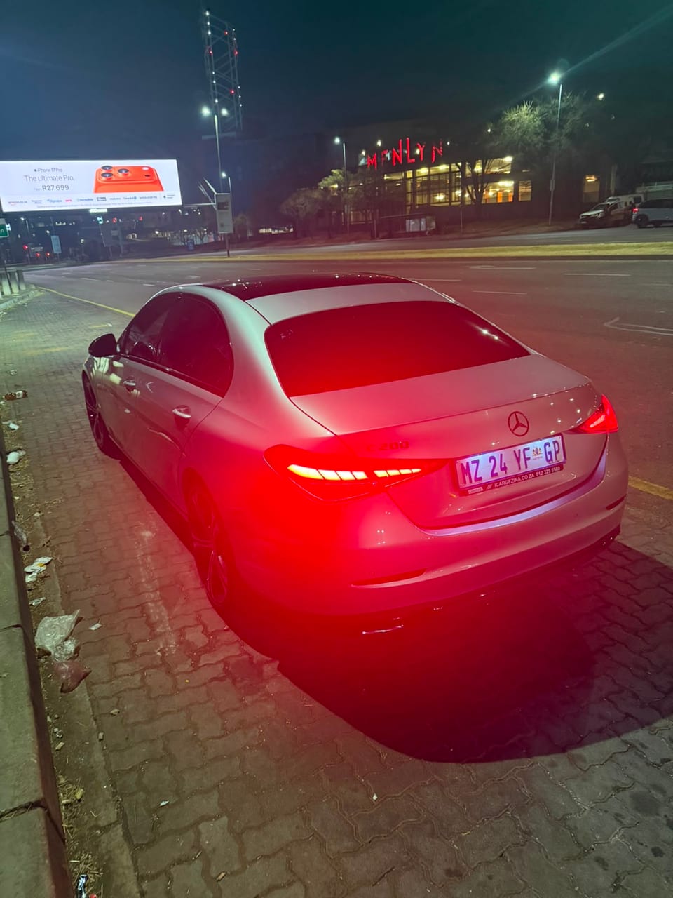 Rear three-quarter view of the car at night, washed red by its own taillights